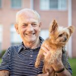 Man and dog GMI Stock - Heritage Oaks of Englewood Man holding yorkshire terrier